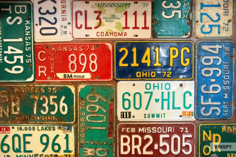 Vintage licence plates displayed on a wall for how to check if a car has been in an accident.
